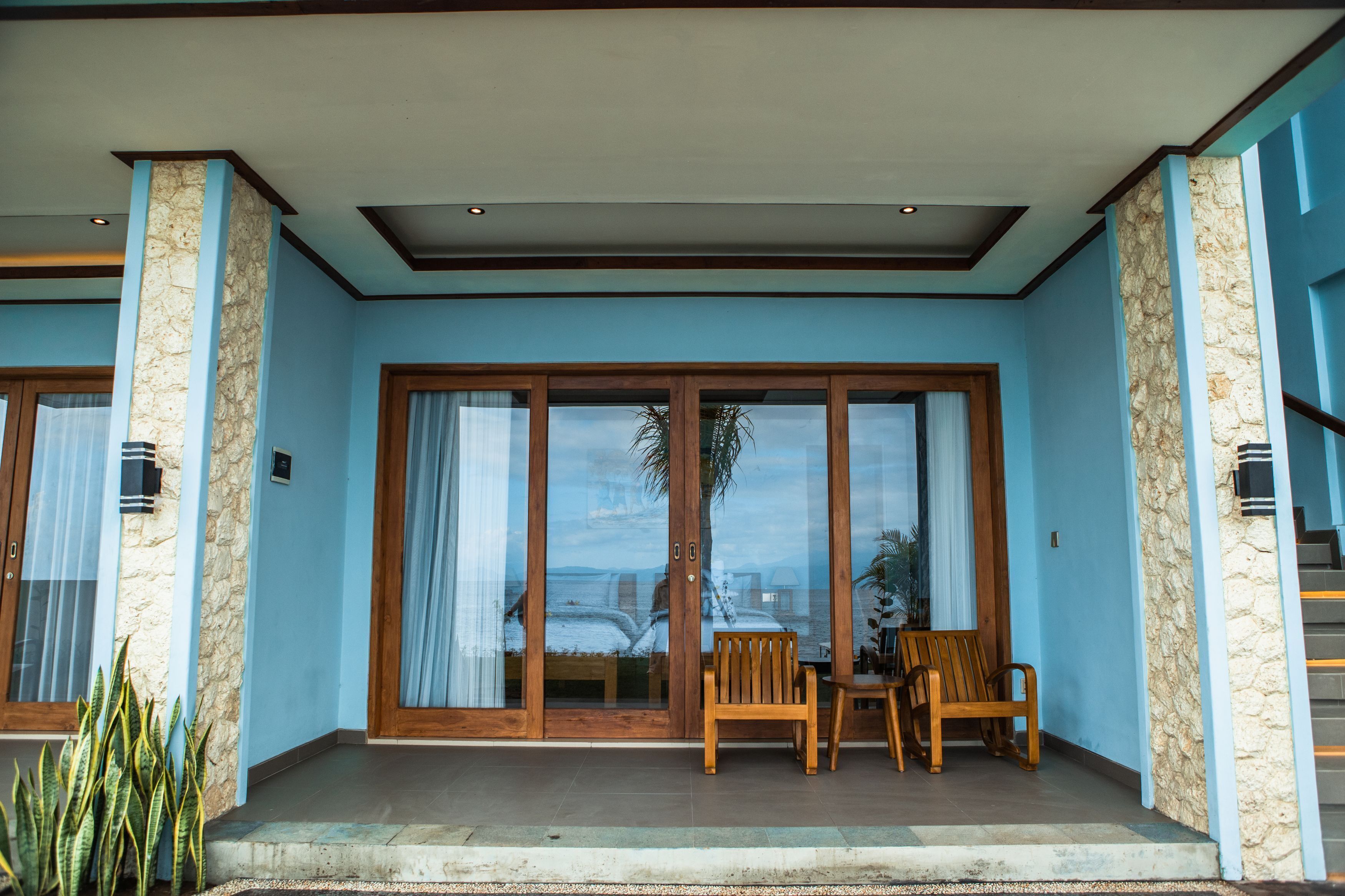 A building with a blue exterior, large glass doors, and a wooden bench outside.