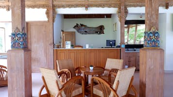 A reception area with a wooden reception desk, wicker chairs, and a decorative wall piece.