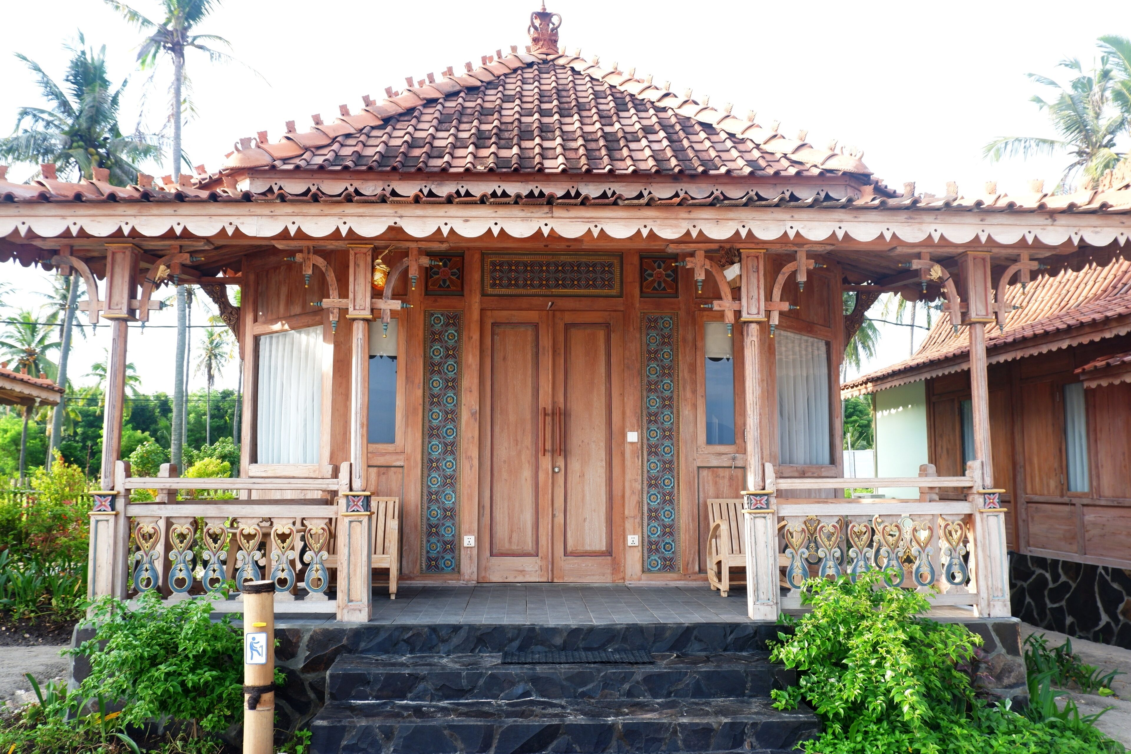 A traditional wooden structure with a tiled roof, a central door, and a decorative railing.