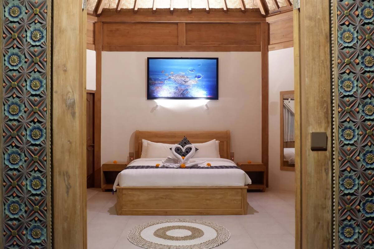 A bedroom with a wooden bed, a wall-mounted TV, and decorative wall panels.