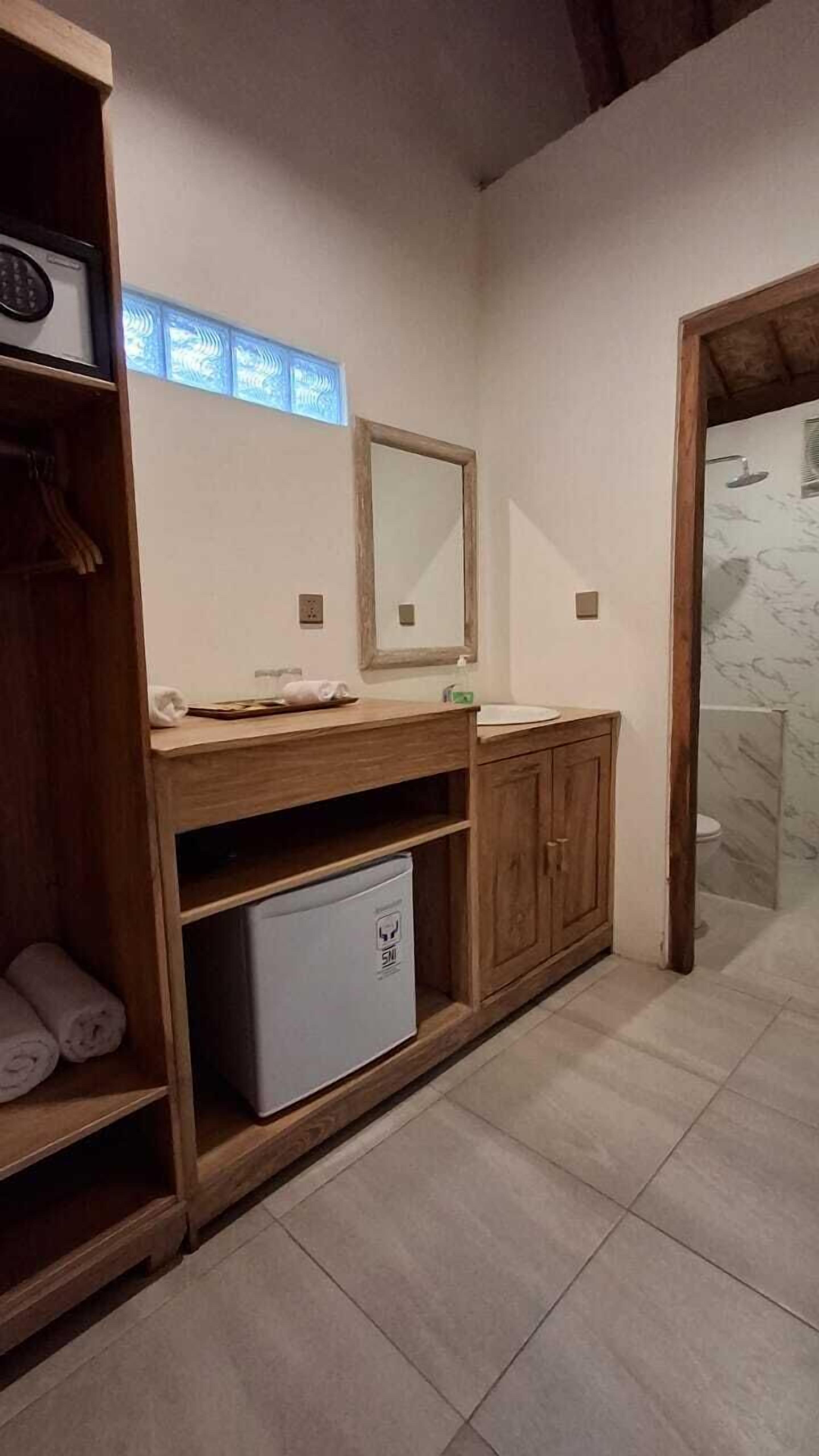 Une salle de bain avec un meuble-lavabo en bois, un miroir, un évier et un espace douche.