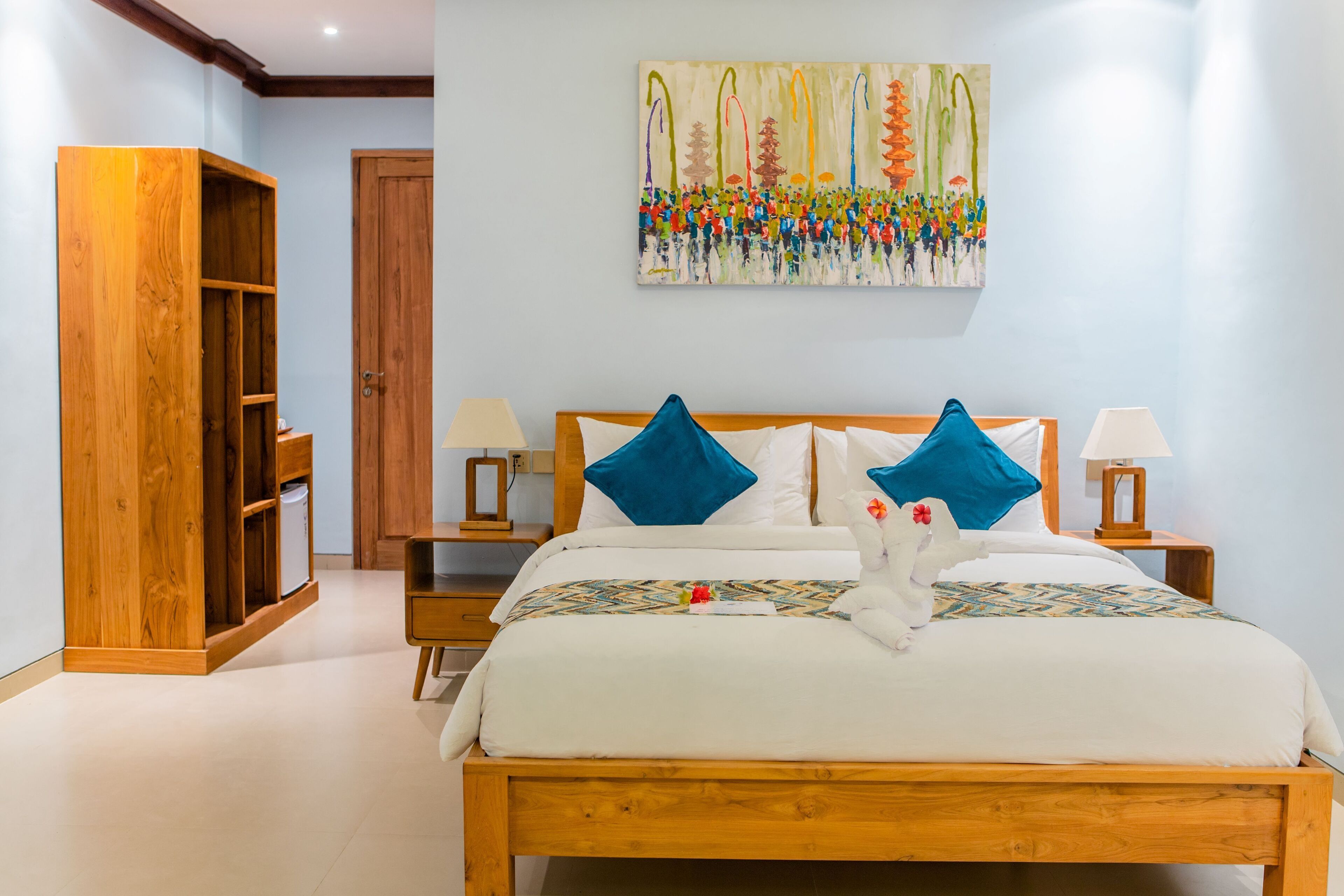 A neatly arranged bedroom with a wooden bed, two nightstands, a wooden wardrobe, and a colorful abstract painting on the wall.