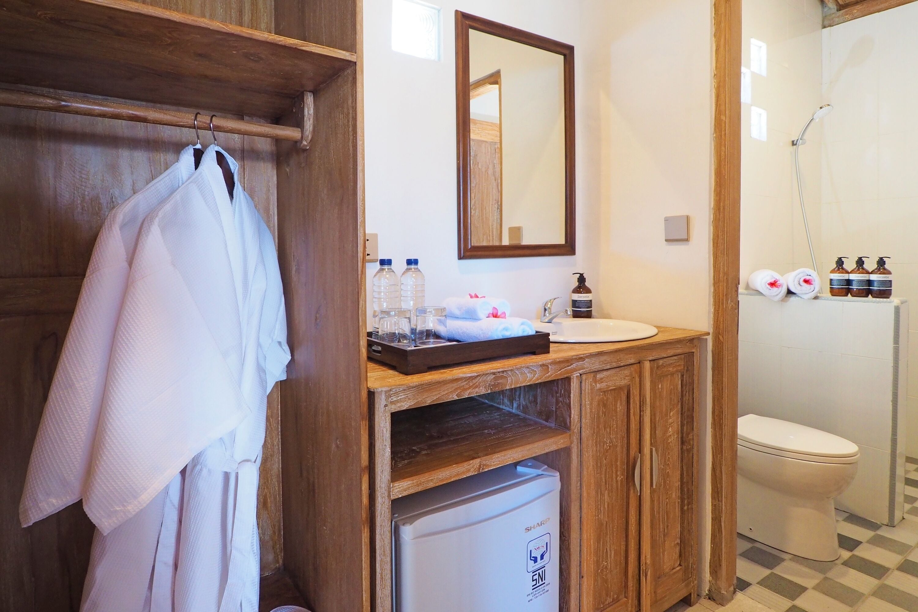 A bathroom with a wooden vanity, a mirror, a sink, a toilet, and a shower area.