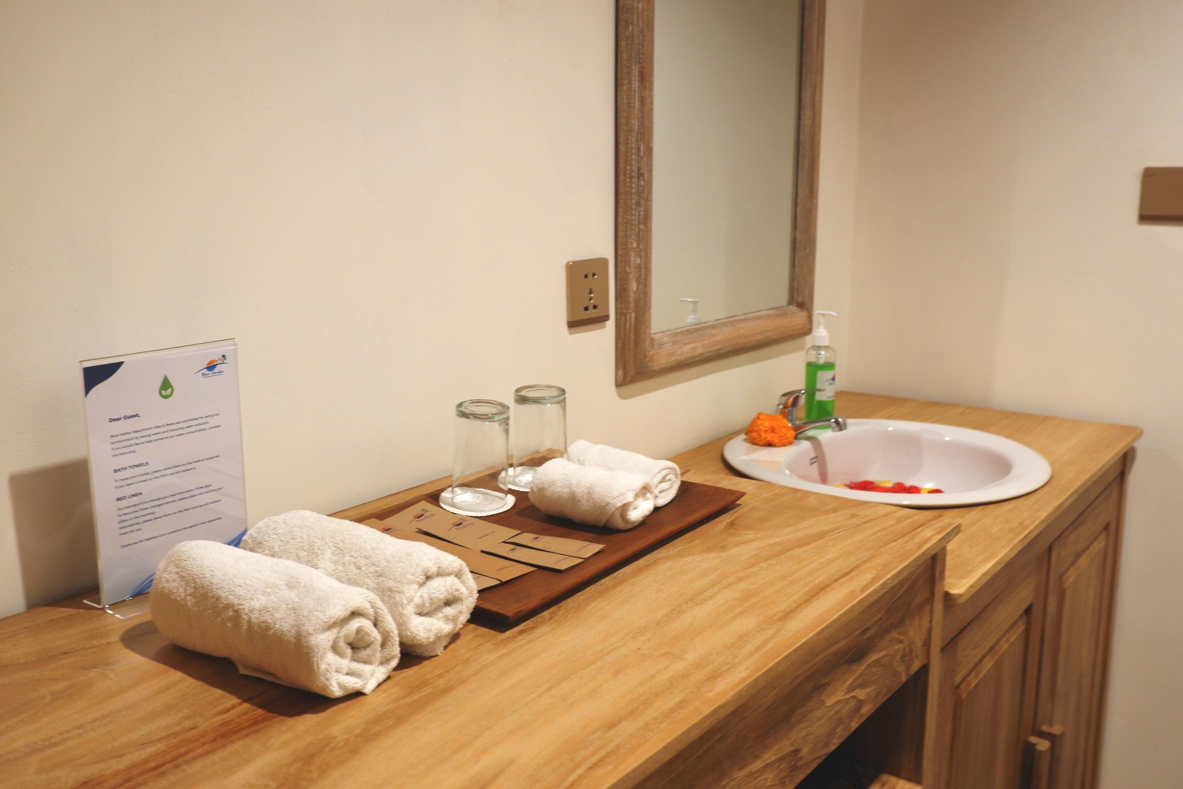 A bathroom with a wooden vanity, a sink, a mirror, and a towel rack.