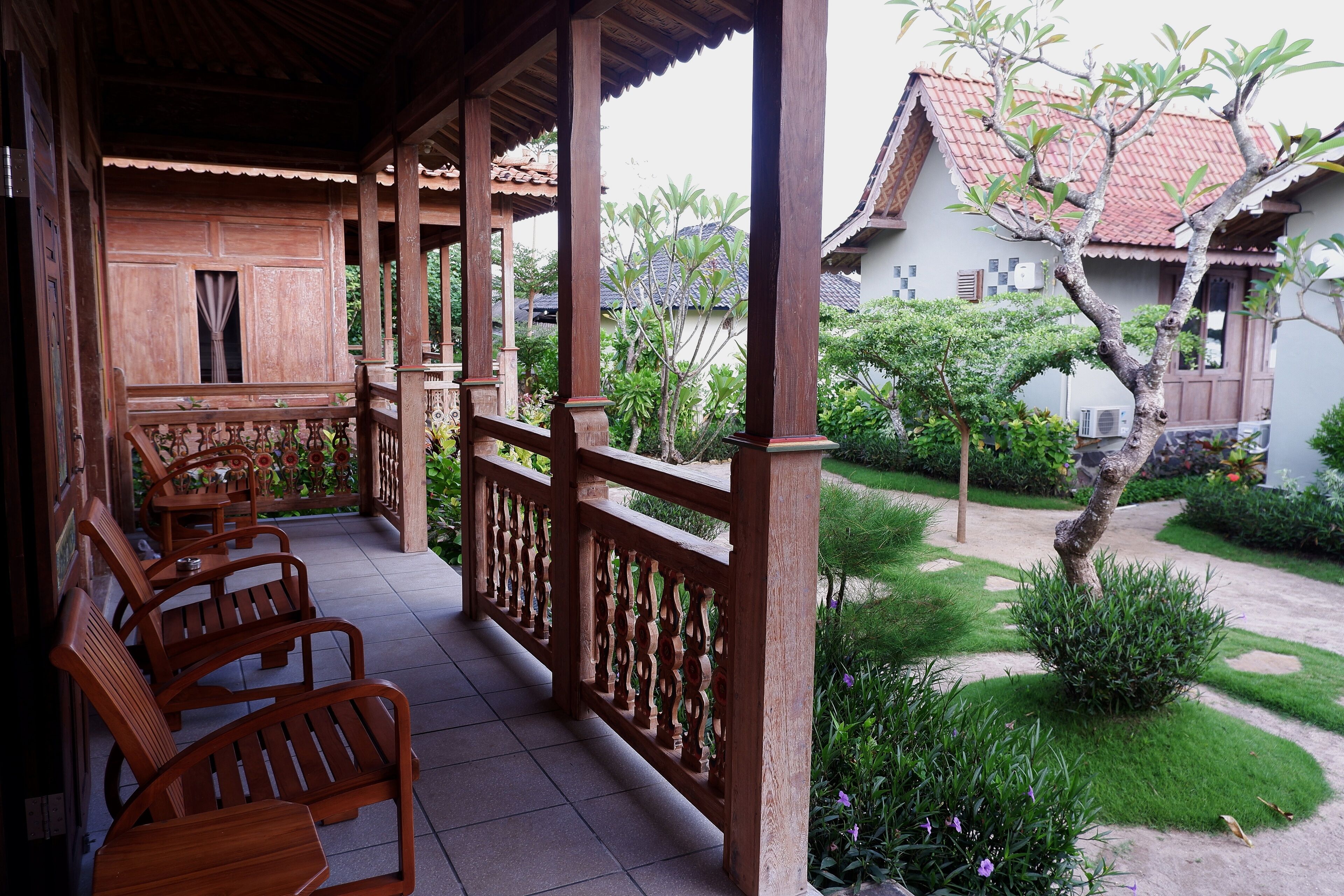 A covered outdoor seating area with wooden chairs and a decorative railing.
