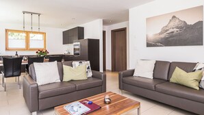 A modern living room with two sofas, a coffee table, and a dining area with a kitchen in the background. - moderen apartment, right on the slopes, Pets welcome, (Zermatt)