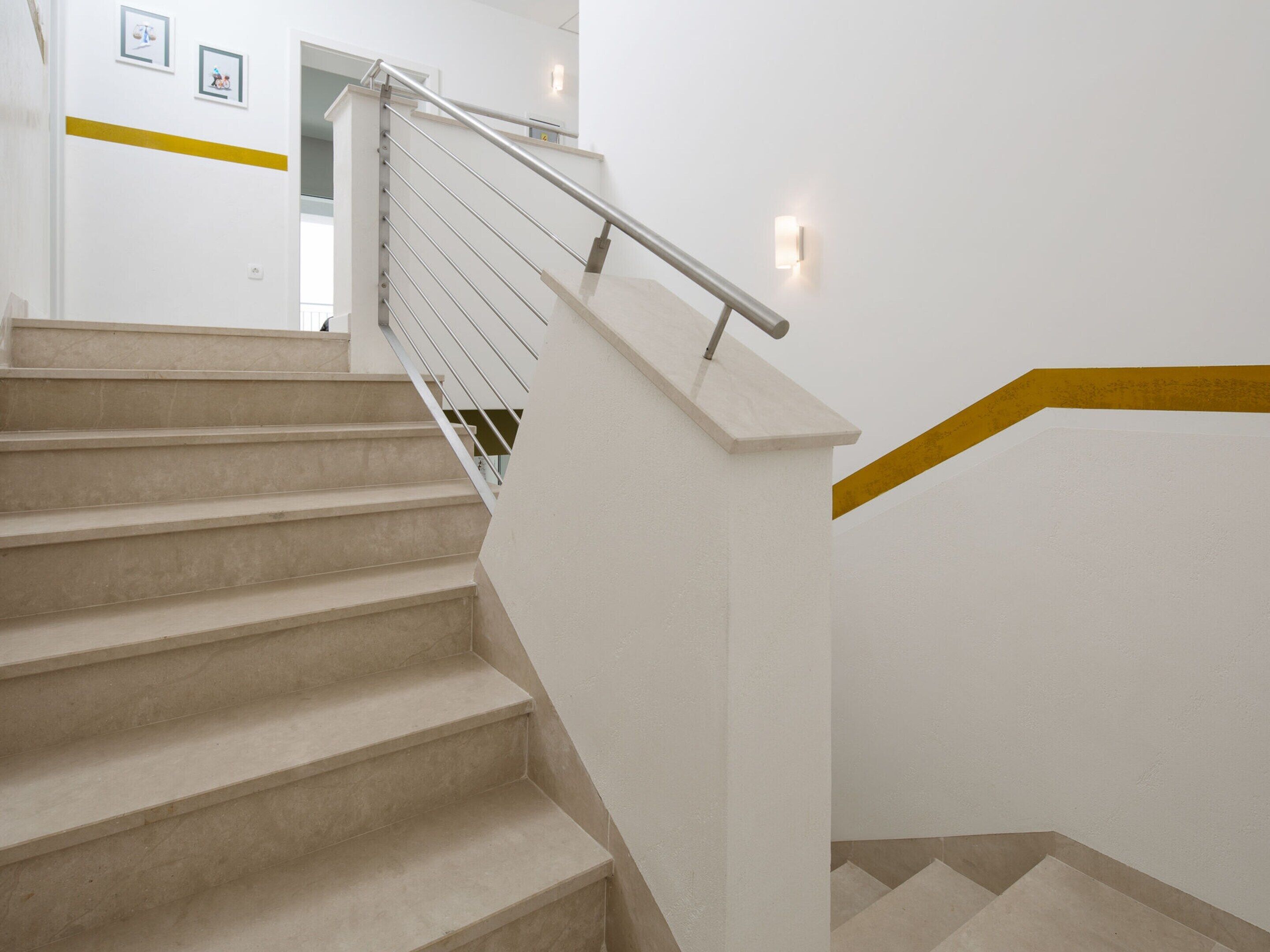 En moderne trappe med gelænder i metal og beige trin.