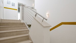 Una escalera moderna con barandilla de metal y peldaños color beige.