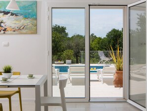 Un salon moderne doté d’une porte-fenêtre coulissante donnant accès à un espace piscine.