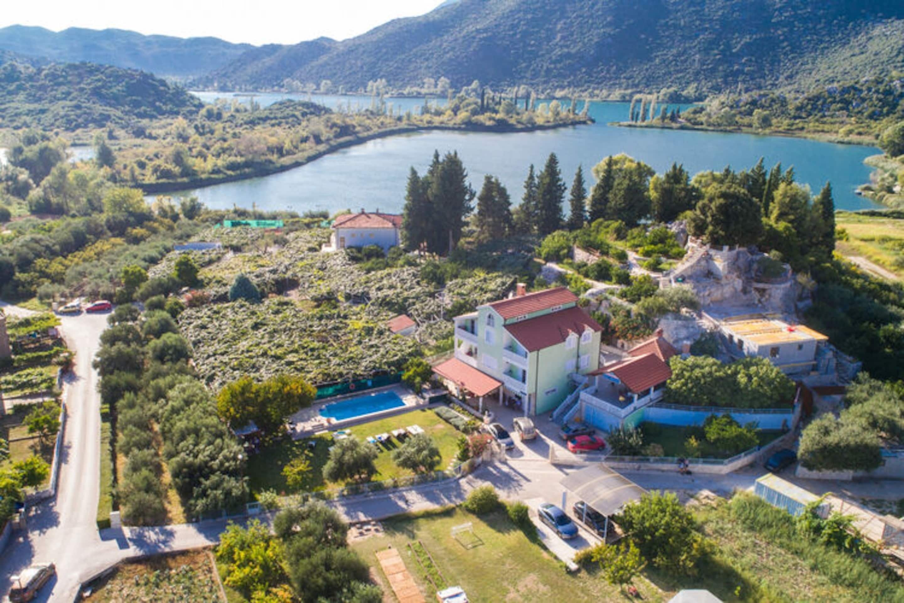 An aerial view of a coastal area with a large building complex, a swimming pool, and a road leading to the sea.