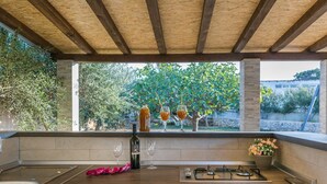 A kitchen with a wooden ceiling, a gas stove, a sink, and a window overlooking a garden. - Spacious Holiday Home With Swimming Pool (Razanac)
