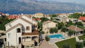 A residential area with a swimming pool, a view of the sea, and mountains in the background. - Spacious Holiday Home With Swimming Pool (Razanac)