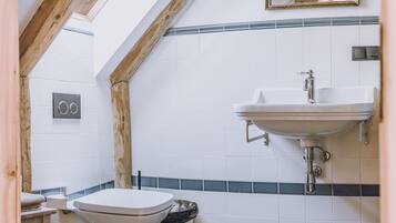 Un baño con inodoro blanco, lavamanos y espejo.