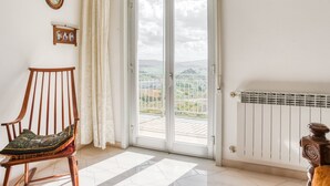 A room with a wooden chair, a large sliding glass door leading to a balcony, and a radiator. - Posh Home in Santa Caterina Villarmosa near Nature Reserve (Santa Caterina Villarmosa)