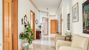 A hallway with a beige sofa, a large vase with flowers, and a wooden door. - Posh Home in Santa Caterina Villarmosa near Nature Reserve (Santa Caterina Villarmosa)