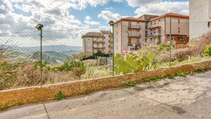A residential area with a chain-link fence, a paved road, and buildings with balconies. - Posh Home in Santa Caterina Villarmosa near Nature Reserve (Santa Caterina Villarmosa)