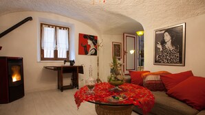 A cozy living room with a fireplace, a table with a red tablecloth, and a sofa with red cushions. - Belvilla by OYO Angie (Sesta Godano)
