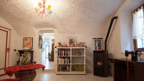 A cozy living room with a fireplace, bookshelves, and a dining area with a red tablecloth. - Belvilla by OYO Angie (Sesta Godano)