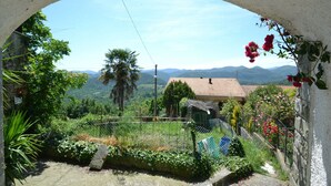 A view through an archway of a rural landscape with a house, greenery, and mountains in the distance. - Belvilla by OYO Angie (Sesta Godano)