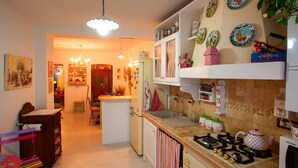 A kitchen with a gas stove, a microwave, and a refrigerator. There is a dining table with chairs and a bookshelf. - Belvilla by OYO Angie (Sesta Godano)