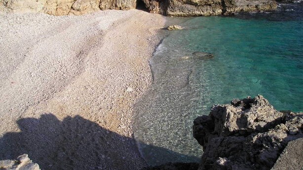 A rocky beach with clear turquoise water and a rocky cliff. - Premium Apartment in Barban With Private Pool (Barban)