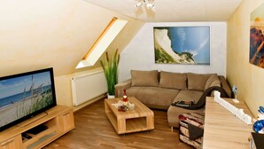 A cozy living room with a television, a sofa, a coffee table, and a wooden cabinet. - Stylish Stay in Kagsdorf (Bastorf)