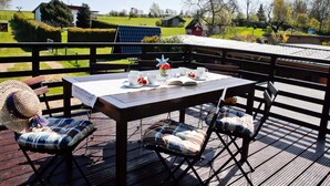 A wooden deck with a table set for two, featuring a book, cups, and a decorative item. - Stylish Stay in Kagsdorf (Bastorf)