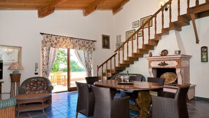 Un salon spacieux avec un escalier en bois, des meubles en osier et une cheminée.
