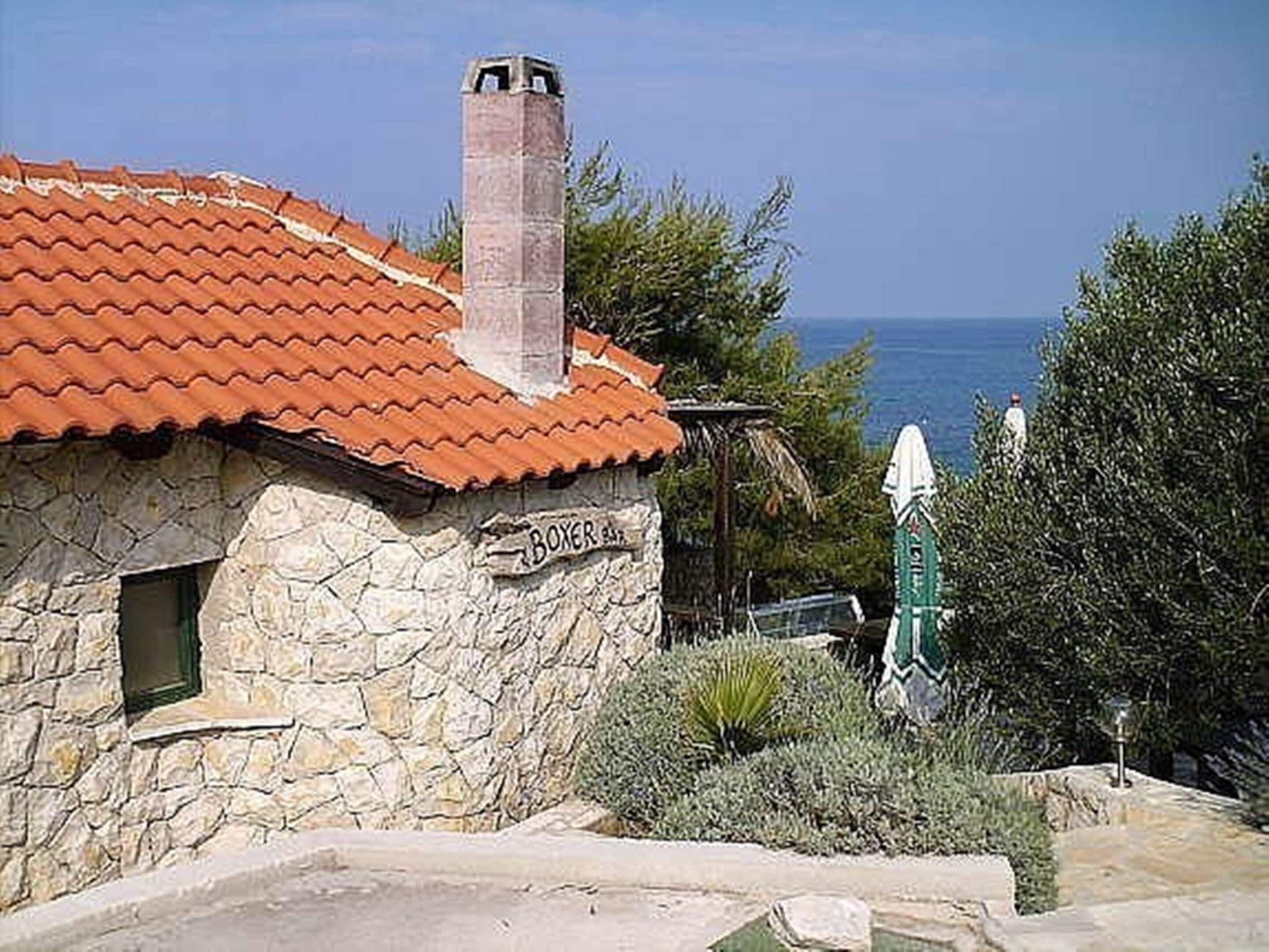A stone building with a red-tiled roof, a chimney, and a sign reading "BOXER".