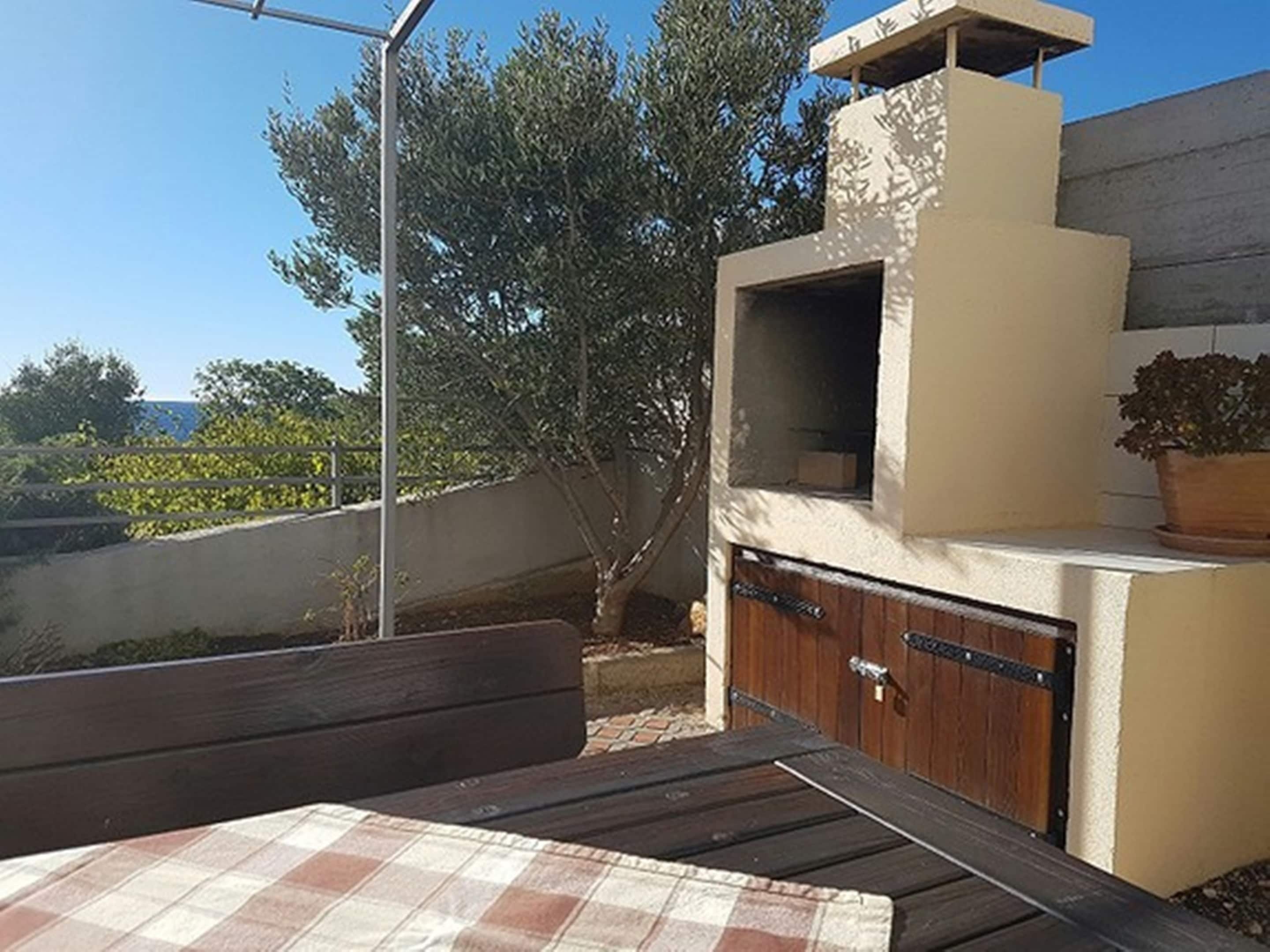 Un patio con un mantel a cuadros, un banco de madera y una parrilla.