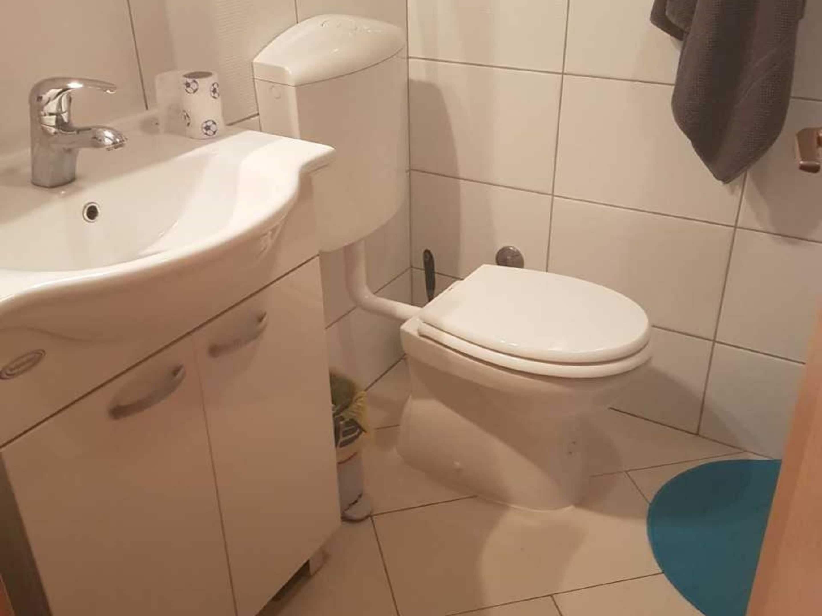A bathroom with a white sink, toilet, and blue bath mat.