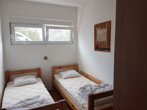 A room with two wooden beds, a window, and a painting on the wall. - Apartment in Dolac Near the Sea (Primosten)