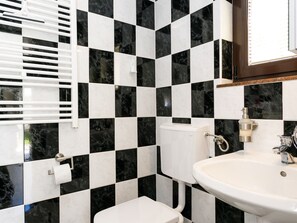 A bathroom with black and white checkered tiles, a white toilet, and a white sink with a mirror above it. - Lovely Apartment With Terrace & Garden Grill (Malinska-Dubasnica)