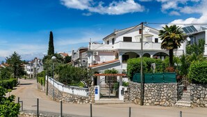 A residential street with stone walls, a gated entrance, and houses with balconies and solar panels. - Lovely Apartment With Terrace & Garden Grill (Malinska-Dubasnica)