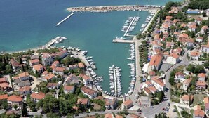 An aerial view of a coastal town with a marina, residential buildings, and a pier. - Lovely Apartment With Terrace & Garden Grill (Malinska-Dubasnica)