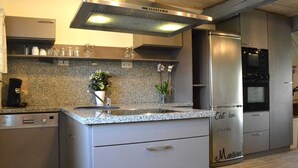A modern kitchen with granite countertops, stainless steel appliances, and a built-in oven. - Group Villa With Sauna (Erezee)