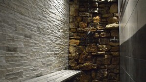 A stone-walled bathroom with a bench and a stone wall feature. - Group Villa With Sauna (Erezee)