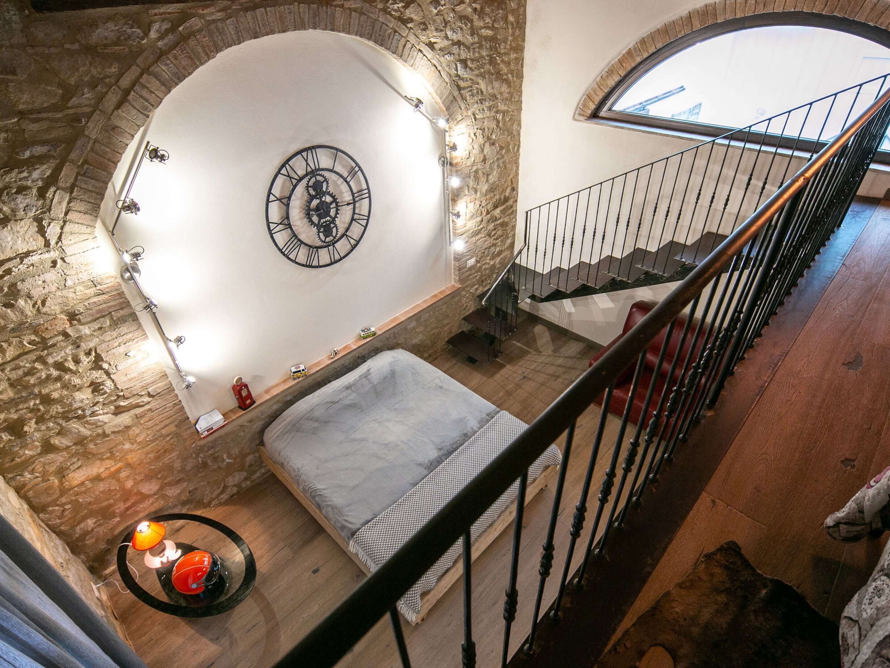 Quarto com cama, relógio de parede redondo e escada.