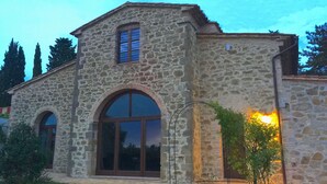 A stone building with a large arched window and a smaller window above it. - Villa in Cortona With Private Pool (Magione)