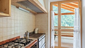 A kitchen with a gas stove, oven, and a view of a wooden deck through a glass door.