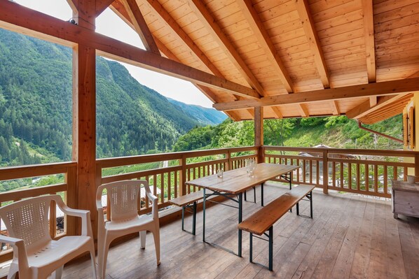 A wooden deck with a table and chairs, overlooking a forested valley.