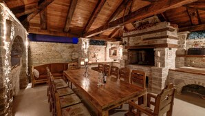 A rustic dining area with a wooden table and benches, stone walls, and a stone fireplace. - Adorable Apartment in Murter with Hot Tub (Murter-Kornati)