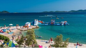 A beach with people, tents, and a water park. - Modern Apartment in Pakostane With Barbecue (Pakostane)