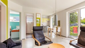 Un salon moderne avec un canapé, une table à manger et des chaises, et un coin cuisine à l’arrière-plan.