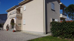 A two-story building with a flat roof, a balcony on the second floor, and a small entrance with a door. - Large Apartment in Malinska near Sea (Malinska-Dubasnica)