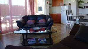 A living room with a leather sofa, a glass coffee table, and a dining area with a white table and chairs. - Large Apartment in Malinska near Sea (Malinska-Dubasnica)