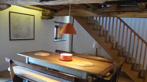 A rustic dining area with a wooden table, benches, and a hanging pendant light.