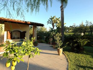 A house with a tiled patio, a small garden with various plants, and a pergola with hanging plants. - Holiday Home With Private Pool, Near the Beach (Trappeto)