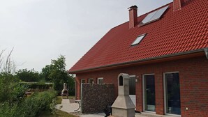 A red-brick house with a sloped roof, a stone chimney, and a stone-built outdoor oven. - Ferienwohnung in Zierow (Zierow)