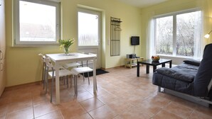Un salon avec un canapé, une table à manger et des chaises, un téléviseur et de grandes fenêtres.